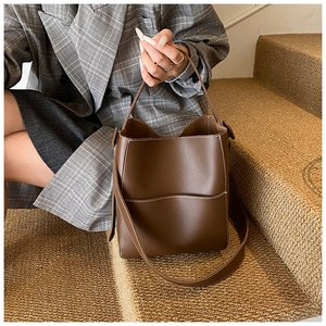 Détails d'un sac seau en cuir marron avec surpiqûres contrastées et bandoulière réglable