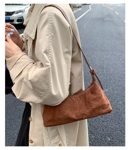 Close-up of deep brown suede crossbody bag showing matte texture and stitching