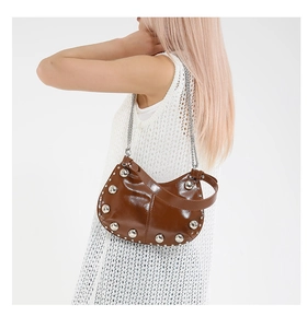 Close-up of brown patent leather underarm bag with silver studs and metal chain strap