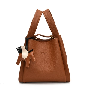 Detailed view of the brown leather bucket bag featuring chic dual handles and horse charm.