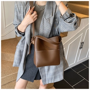 Brown leather bucket bag detail with white contrast stitching and adjustable crossbody strap
