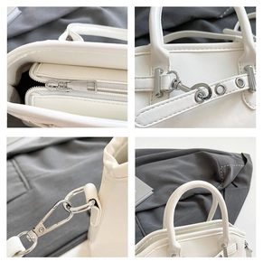 Close-up of white shell bag with silver hardware, top zipper and detachable strap hooks