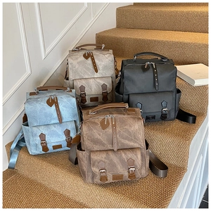 Collection of vintage canvas backpacks in grey black blue and brown on rustic stairs