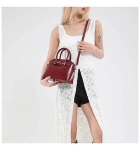 Detail of burgundy leather tote bag showing reinforced handles and silver metal hardware buckle