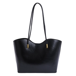 Vue de face d'un grand sac cabas noir minimaliste avec des détails en métal doré chic