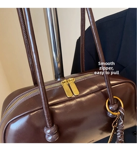 Detailed close-up of smooth double gold zippers on a vintage brown leather bowling bag