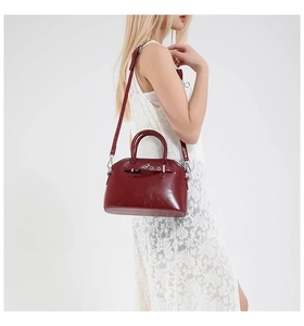 Model wearing a wine red shell-shaped handbag with polished oil wax leather texture