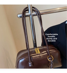 Close-up of glossy brown bowling bag showing gold dual-zipper and metallic hardware