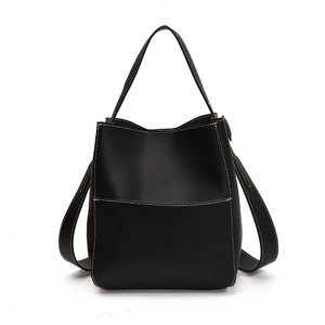 Minimalist black leather bucket bag with white contrast stitching and a front pocket