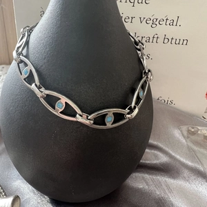 Hip hop titanium steel chain necklace with light blue stones on a vintage black vase