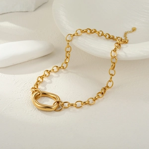 Polished gold chunky chain necklace with oval buckle on white textured surface