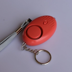 Detail of red personal safety alarm with woven lanyard, metal keyring, and LED light