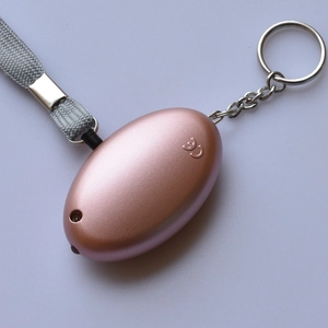 Detail view of rose gold personal safety alarm with CE certification and woven lanyard