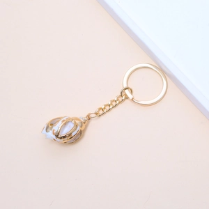 Detail showing natural sea shell in gold metal frame hanging on a golden keychain