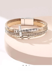 Detail of multi-layer leather bracelet with BLESSED engraved cross and crystal inlay