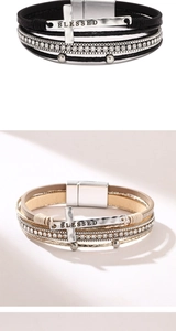 Detail of bohemian leather bracelets with rhinestone cross and 'BLESSED' magnetic buckle