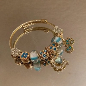 Golden handmade beaded bracelet with blue charms like moon heart and snowflake designs