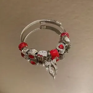 Macro view of stainless steel beaded bracelet with red glass beads and kitty charm