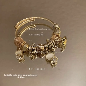 Detail of gold beaded bracelet with musical and paw charms for 13-16cm wrists