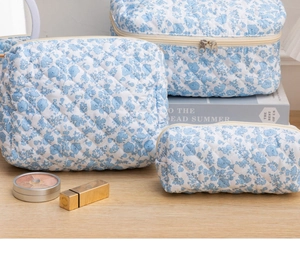 Detailed view of three-piece quilted floral makeup bags on a wooden table setup