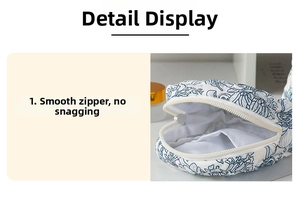 Detail view of smooth white nylon zipper and blue floral pattern on quilted cotton bag