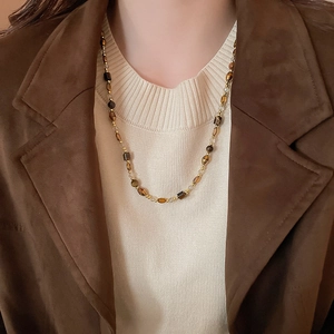 Macro shot of tiger eye stone pendant necklace with brown beads on a knitted sweater