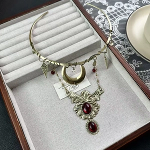 Detail of vintage bronze fringe necklace with red gemstones and crescent moon pendant