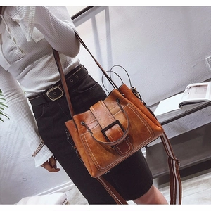 Retro brown leather bucket bag with square buckle and striped strap on model