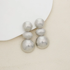 Detail of silver matte triple ball drop earrings with elegant metallic texture
