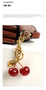 Detailed close-up of a glittering red cherry keychain hanging on a brown leather handbag