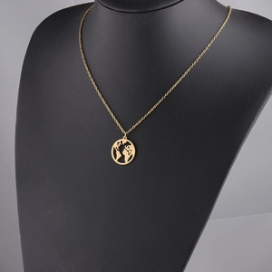 Detail of a golden world map pendant on a black mannequin featuring a fine O-chain necklace