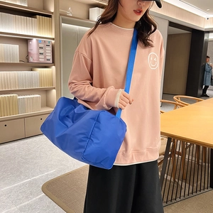 Grande borsa da viaggio blu reale impermeabile indossata da una modella in interni casual