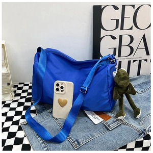 Primo piano della borsa in nylon blu elettrico con un simpatico portachiavi a rana verde