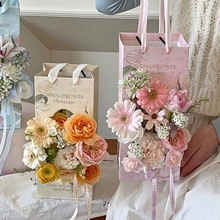 Close-up of elegant flower gift bags in pink and cream with roses and gerbera daisies