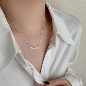 Minimalist feather leaf pendant necklace in silver, shown on model with white shirt