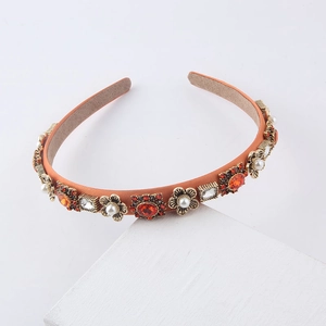 Macro shot of orange satin headband with vintage crystals and pearls on white stone