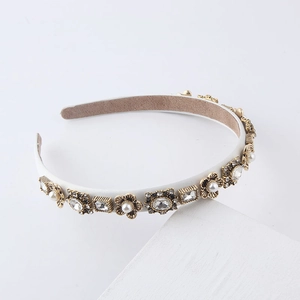 Detailed view of baroque pearl and rhinestone embellishments on a white fashion headband