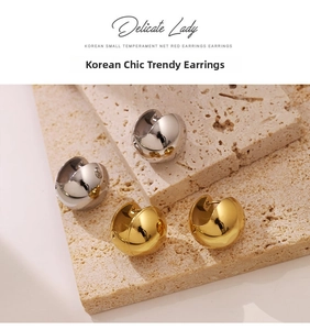Polished gold and silver hollow ball earrings displayed on elegant textured stone surface
