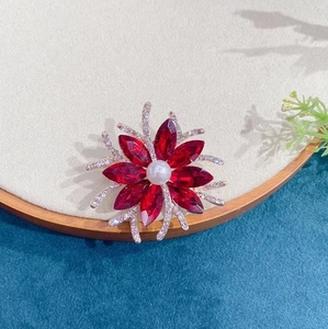Radial flower brooch with red marquise crystals and a central white pearl inlay