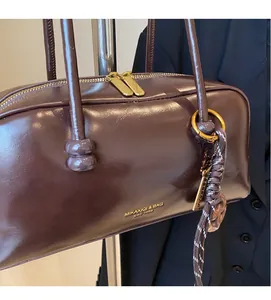 Close-up of dark brown vintage bowling bag with glossy leather texture and gold hardware