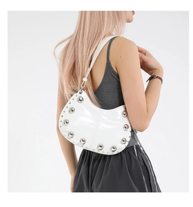 Détail du sac croissant en cuir verni blanc avec rivets argentés style Y2K