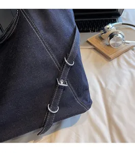 Détail d'un sac en denim bleu avec anneaux argentés et surpiqûres contrastées