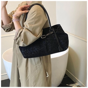 Detail of black leopard print tote bag with leather handles shown on a model