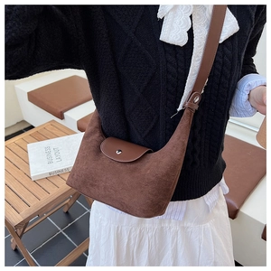Détail de la sacoche en daim marron montrant le rabat en cuir et le fermoir en métal