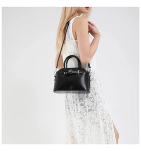 Detail view of black glossy shell bag with silver hardware on model with lace dress