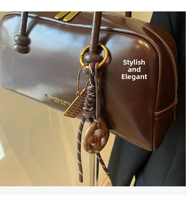 Detail of dark brown leather handbag with gold zipper and miniature abacus charm