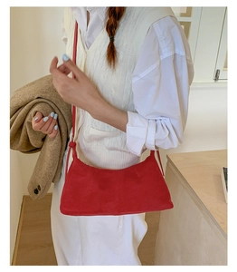 Close-up of red suede underarm bag with minimalist stitching and slim shoulder strap