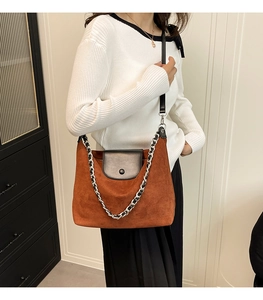 Close-up of brown suede hobo bag with black leather flap and silver chain detail