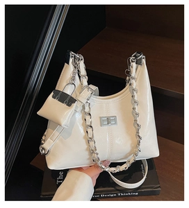 Detail of white patent leather hobo bag with silver chain and mini pouch charm