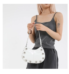 Détail du sac demi-lune en cuir verni blanc avec décorations de gros rivets métalliques
